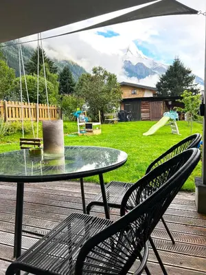 a patio with a table and chairs and a playground at Le point de vue in Chamonix-Mont-Blanc