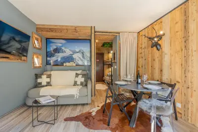 a dining room and living room with a table and chairs at Chalet studio Megève enface des remontées mécaniques et parking gratuit in Demi-Quartier