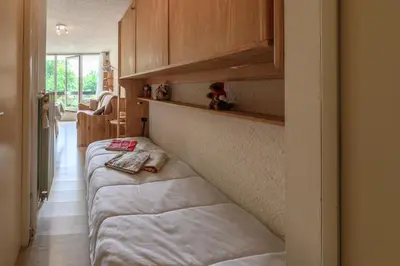 a bedroom with two beds and wooden cabinets at Le Pré du bois des Carroz - Proche Aquacîme in Arâches-la-Frasse