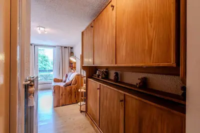 a kitchen with wooden cabinets and a living room at Le Pré du bois des Carroz - Proche Aquacîme in Arâches-la-Frasse