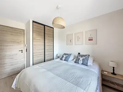 a white bedroom with a bed and a window at DBA202 - Appartement standing 4-5 pers in Les Carroz d'Araches