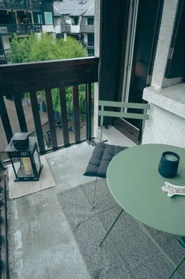 a balcony with a white table and a view of a building at Le Perchoir d'Edmond in Chamonix-Mont-Blanc