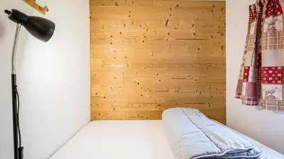 a room with a bed with a lamp and wooden wall at Grande Neige N 10 - 2P4 in Morillon