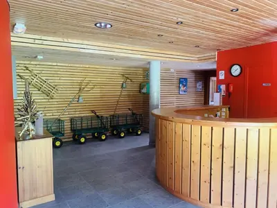 a lobby with a wooden wall with a waiting room with carts at Les 3 balcons du Mont Joly in Les Contamines-Montjoie