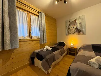 a bedroom with two beds and a picture of a wolf at Joli appartement 2 chambres Belle Vue, Les Houches in Les Houches
