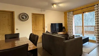 a living room with a couch and a table and a television at Joli appartement 2 chambres Belle Vue, Les Houches in Les Houches