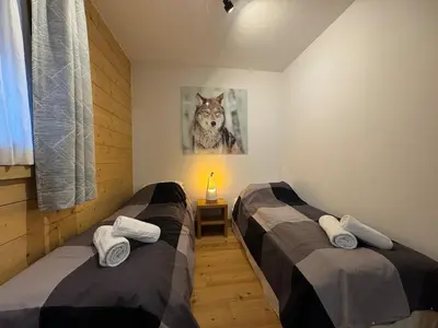 two beds in a room with a wolf picture on the wall at Joli appartement 2 chambres Belle Vue, Les Houches in Les Houches