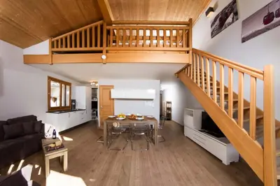 a living room with a table and a staircase at Sauberands 18 apartment - Chamonix All Year in Chamonix-Mont-Blanc