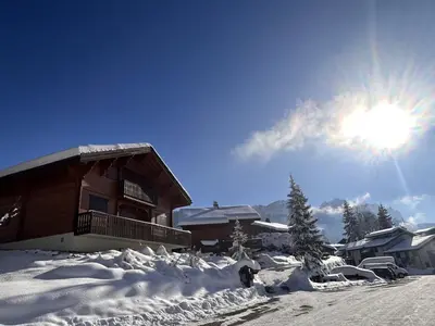a snow covered house with the sun in the sky at Chalet typique 5 chambres pour 10 personnes avec Wi-Fi et terrasse - FR-1-572-303 in Arâches-la-Frasse