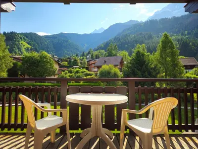 a table and chairs on a deck with a view of mountains at Appartement 4-6 personnes centre Les Contamines Montjoie in Les Contamines-Montjoie