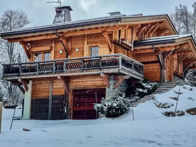 a log cabin with a deck in the snow at Chalet des Sommets in Combloux