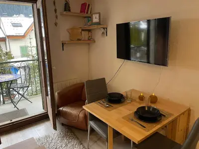a living room with a table and a television on the wall at Downtown Chamonix Studio & Stunning Mountain View in Chamonix-Mont-Blanc