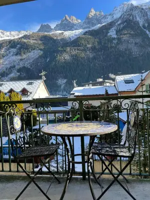 a table and chairs on a balcony with snow covered mountains at Downtown Chamonix Studio & Stunning Mountain View in Chamonix-Mont-Blanc
