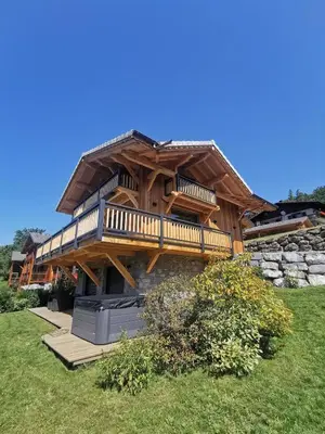 a large wooden house with a deck on a field at Chalet Le M - Adults only - Standing - Samoëns Grand-Massif in Samoëns