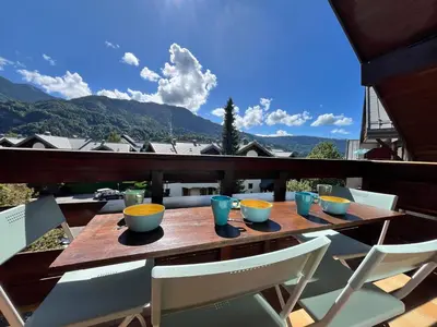 a wooden table with bowls and chairs on a balcony at Studio cosy au centre de Samoëns, animaux acceptés - FR-1-624-183 in Samoëns