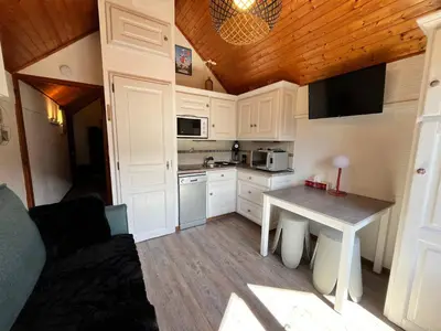 a small kitchen with white cabinets and a table at Studio cosy au centre de Samoëns, animaux acceptés - FR-1-624-183 in Samoëns