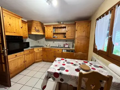 a kitchen with a table and a kitchen with wooden cabinets at Chalet chaleureux au pied des pistes avec animaux acceptés - FR-1-624-184 in Samoëns