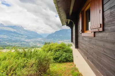 a house with a window and a view of mountains at L'Écrin des Anges Chalet cosy, Ski et Vue in Combloux