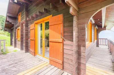 a wooden house with a wooden door on a deck at L'Écrin des Anges Chalet cosy, Ski et Vue in Combloux