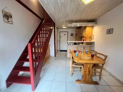 a kitchen and dining room with a wooden table and a staircase at Charmant T2 Mezzanine au Centre de Samoëns avec Balcon, WIFI - FR-1-624-182 in Samoëns