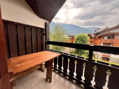 a wooden bench on a balcony with a view at Charmant T2 Mezzanine au Centre de Samoëns avec Balcon, WIFI - FR-1-624-182 in Samoëns