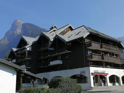 a large black building with a mountain in the background at Charmant T2 Mezzanine au Centre de Samoëns avec Balcon, WIFI - FR-1-624-182 in Samoëns
