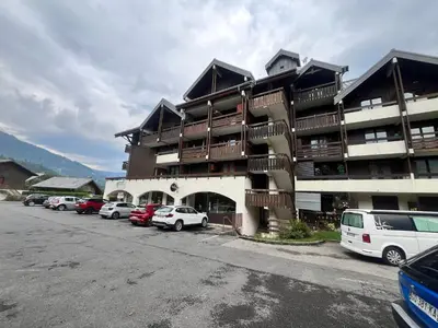 a large building with cars parked in a parking lot at Charmant T2 Mezzanine au Centre de Samoëns avec Balcon, WIFI - FR-1-624-182 in Samoëns