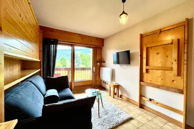 a living room with a blue couch and a tv at La Pierre Enneigée in Combloux