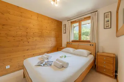 a bedroom with a white bed and a window at Appartement Les Capucins jardin - Happy Rentals in Chamonix-Mont-Blanc
