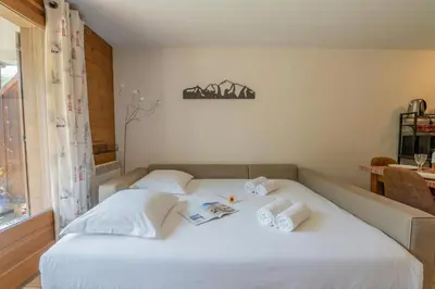 a bedroom with a large white bed and a window at Appartement Les Capucins jardin - Happy Rentals in Chamonix-Mont-Blanc