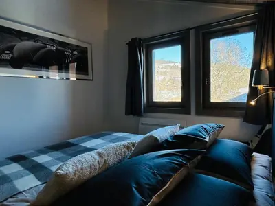 a bedroom with a bed and two windows at Séjour lumineux avec vue sur les cimes in Megève