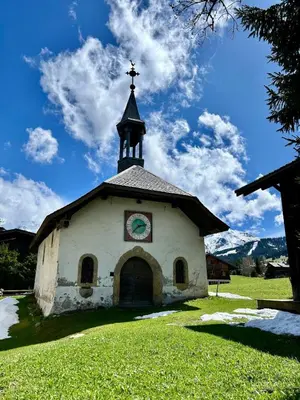 a church with a steeple with a clock on it at Séjour lumineux avec vue sur les cimes in Megève