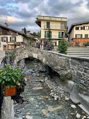 a stone bridge over a stream with flowers on it at Séjour lumineux avec vue sur les cimes in Megève