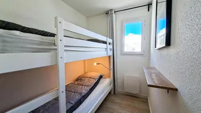 a bedroom with two bunk beds and a desk at Résidence Doris - Appartement rénové · Centre station · Balcon · WIFI gratuit MAE-4483 in Magland