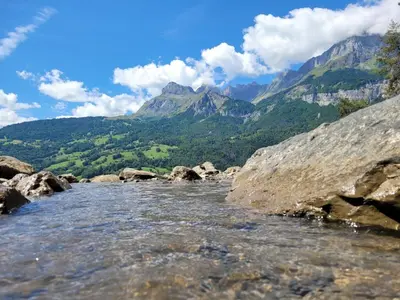 a river with rocks and mountains in the background at Studio cosy & rénové, à deux pas de la gare in Sallanches