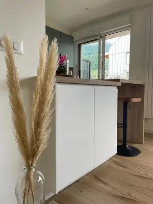 a kitchen with white cabinets and a vase with dry grass at Studio cosy & rénové, à deux pas de la gare in Sallanches