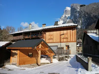 a large wooden building in the snow with a mountain at Chalet confortable pour 10 pers à Samoëns avec parking et terrasse - FR-1-815-47 in Samoëns
