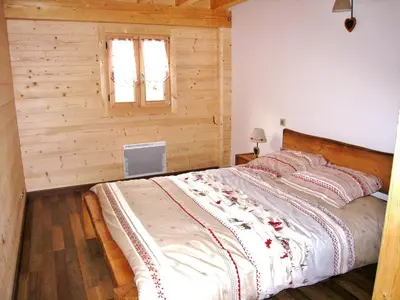 a large bed in a room with a wooden wall at Chalet confortable pour 10 pers à Samoëns avec parking et terrasse - FR-1-815-47 in Samoëns