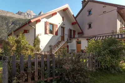 a house with a fence and mountains in the background at Le Nevada - Duplex T4 Proche Centre in Chamonix-Mont-Blanc