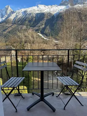 a picnic table and two chairs on a balcony with mountains at Le Nevada - Duplex T4 Proche Centre in Chamonix-Mont-Blanc