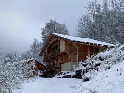 a log cabin in the snow with a snow covered driveway at Le Chalet MontBlanc in Bionnay