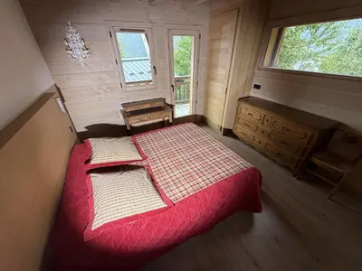 a bedroom with a red bed and a window at Le Chalet MontBlanc in Bionnay
