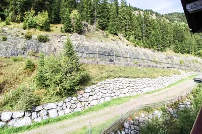 a mountain road with a rock wall and trees at Unique appartement 2 chambres derniere etage Les Terrasses dEos in Flaine