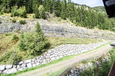a mountain road with a rock wall and trees at Unique appartement 2 chambres derniere etage Les Terrasses dEos in Flaine