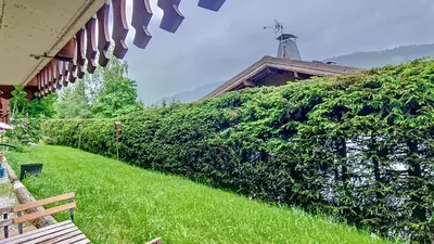 a hedge with a bench next to a building at 1 Farniente in Megève