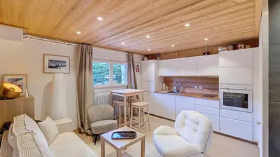 a living room with a kitchen with white cabinets at 1 Farniente in Megève