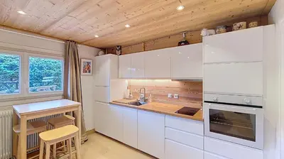a kitchen with white cabinets and a sink and a table at 1 Farniente in Megève