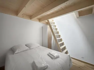 a bed in a small room with a staircase at DBA302 Appartement standing 6 pers in Les Carroz d'Araches