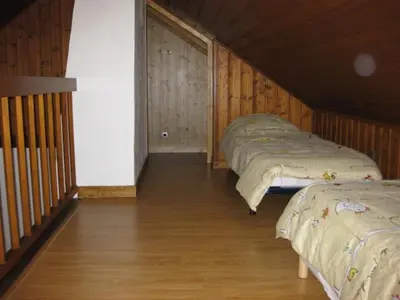 two beds in a room with wooden walls and wood floors at Appartement Léa in Chamonix-Mont-Blanc
