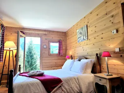 a bedroom with a bed with wooden walls and a window at Chalet near centre of Megève in Megève